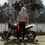 Tattooed Man Standing in Front of a Motorbike