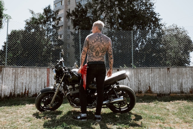 Tattooed Man Standing in Front of a Motorbike